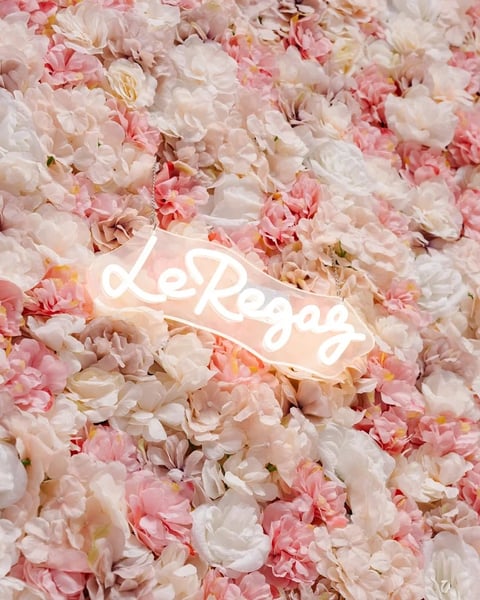 Neon love sign glowing white on a bed of pink and white peonies